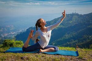 Sorty fit woman doing yoga asana outdoors in mountains photo