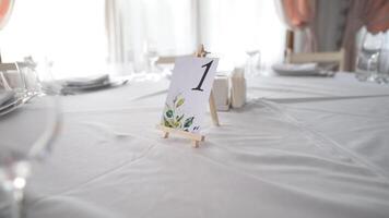 mesa número dentro restaurante servido com talheres é preparado para festivo evento sem pessoas e Comida. Casamento mesa decorado. convidado mesa número. Casamento mesa dentro a restaurante. casamento. banquete. video