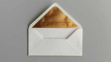 An envelope with gold foil on it, with the top open placed against a gray background. photo