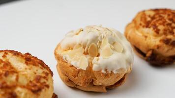 Freshly baked cream puffs or Vanilla eclairs with cream and nuts topping isolated on white background photo