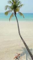 Woman swings on a palm tree on tropical sandy beach in Thailand video