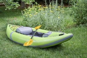 green inflatable whitewater kayak with paddle photo
