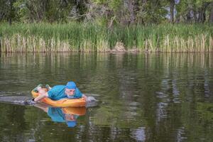 athletic, senior man is paddling a prone kayak photo