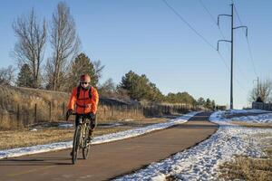 senior male cyclist is riding a touring bike in winter scenery photo