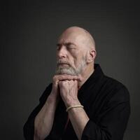 senior man with closed eyes meditating or praying photo