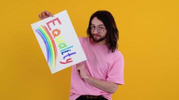 Attractive bearded gay caucasian man holding a protest sign during a LGBT pride parade. Equality concept video