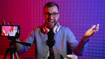 Portrait of a blogger with headphones and condenser microphone in a home studio. Male blogger recording voice over radio video