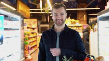 portrait de une homme avec achats panier à supermarché. homme choisir le droite produit dans une supermarché video