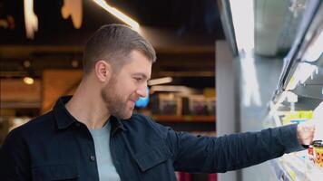 Young glad cheerful positive smiling male customer choosing milk and dairy products in grocery, family shopping video