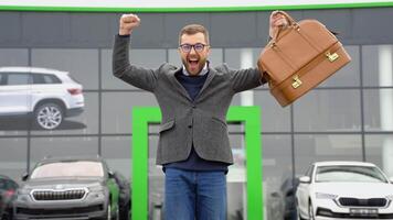 ein Mann zeigt an Emotionen von Glück nach Kauf ein Neu Auto in der Nähe von ein Auto Händler video