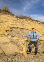 mayor masculino palista vistiendo vida chaqueta con un de madera canoa paleta en un rocoso lago apuntalar foto