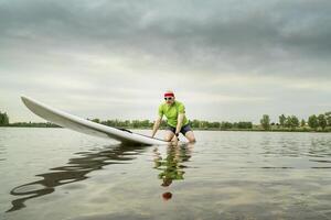 senior paddler on stand up paddleboard photo