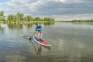 senior paddler on stand up paddleboard photo