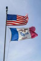 americano y estado de Iowa banderas con orgullo ondulación y revoloteando en un fuerte viento foto