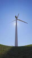 rotierend Klingen von ein Windmühle Propeller auf Blau Himmel Hintergrund mit Sonne Strahlen. Wind Leistung Generation. rein Grün Energie. video