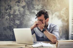 Overwhelmed businessman facing financial crisis in a rustic office setting at dusk photo