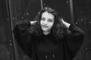 White brunette teenage girl with curly hair poses on the street in the city. photo