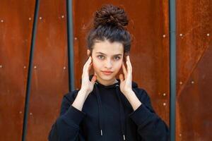 White brunette teenage girl with curly hair poses on the street in the city. photo