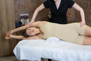 Young attractive Caucasian woman receiving professional rehabilitation procedure in medical office. Therapist doing healing treatment on woman's back. photo