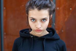 White brunette teenage girl with curly hair poses on the street in the city. photo