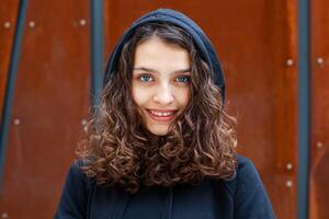 White brunette teenage girl with curly hair poses on the street in the city. photo