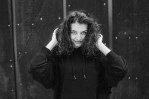 White brunette teenage girl with curly hair poses on the street in the city. photo