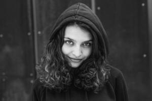 White brunette teenage girl with curly hair poses on the street in the city. photo