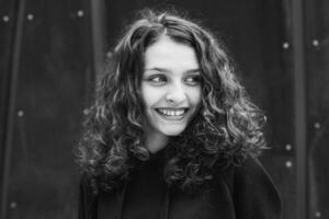 White brunette teenage girl with curly hair poses on the street in the city. photo