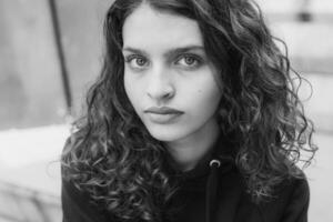 White brunette teenage girl with curly hair poses on the street in the city. photo