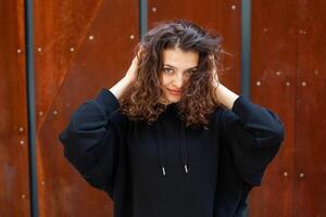 White brunette teenage girl with curly hair poses on the street in the city. photo