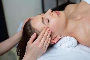 hermosa joven mujer consiguiendo facial masaje en spa salón. belleza tratamiento concepto. foto