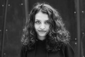 White brunette teenage girl with curly hair poses on the street in the city. photo