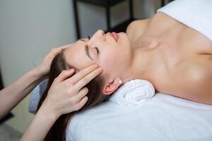 hermosa joven mujer consiguiendo facial masaje en spa salón. belleza tratamiento concepto. foto