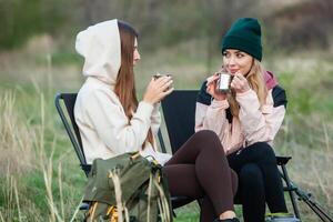 Two young women hiking in the mountains and drinking tea from a kettle. Travel, traveler. photo