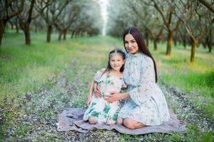 A happy family. Mother and daughter rest in the park in dresses photo