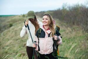 Two young women hiking in the mountains and drinking tea from a kettle. Travel, traveler. photo