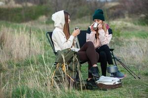 Two young women hiking in the mountains and drinking tea from a kettle. Travel, traveler. photo