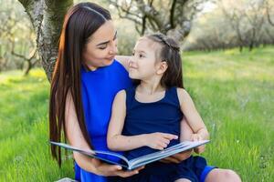 mother and daughter are reading together in the park photo