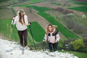 Two young women hiking in the mountains and drinking tea from a kettle. Travel, traveler. photo