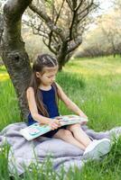 a child girl is reading a book in the park photo