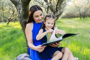 mother and daughter are reading together in the park photo