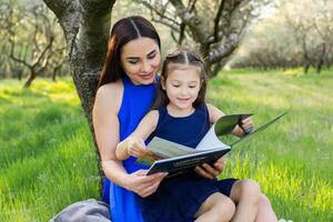 mother and daughter are reading together in the park photo