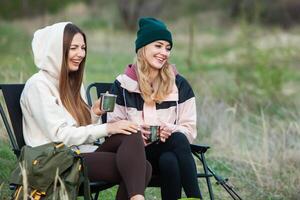 Two young women hiking in the mountains and drinking tea from a kettle. Travel, traveler. photo