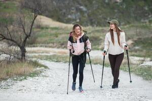 dos joven mujer excursionismo en el montañas y Bebiendo té desde un pava. viajar, viajero. foto