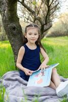 a child girl is reading a book in the park photo