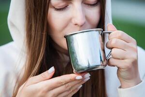 retrato de un hermosa joven mujer con taza de té al aire libre. foto