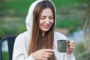 Portrait of a beautiful young woman with cup of tea outdoors. photo