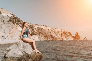 Woman travel summer sea. A happy tourist in a blue bikini enjoying the scenic view of the sea and volcanic mountains while taking pictures to capture the memories of her travel adventure. photo