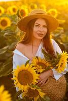 un niña en un sombrero en un hermosa campo de girasoles en contra el cielo en el noche ligero de un verano puesta de sol. rayos de sol mediante el flor campo. natural antecedentes. foto