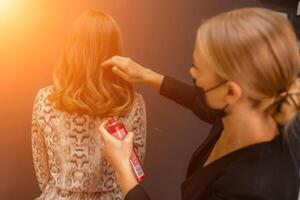 mujer salón peinado. peluquero usos laca para el cabello en clientela pelo en salón, retrato de dos hermosa mujer foto